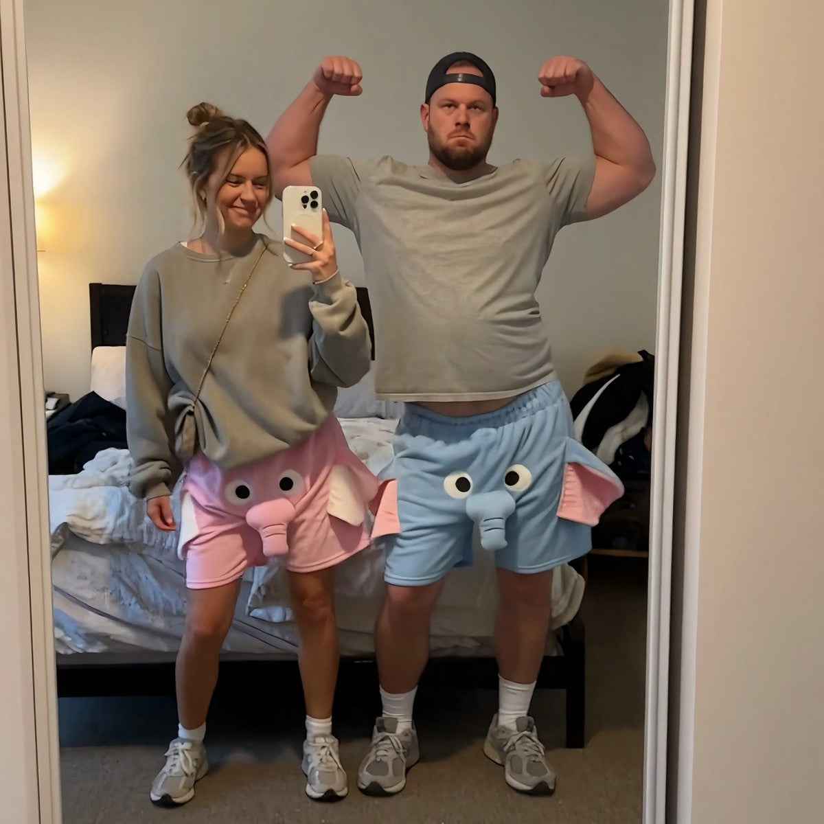 Couple wearing pink and blue elephant shorts in the mirror
